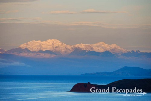 Sunset over Lake Titicaca with a part of Isla de la Luna in the front and the snow-capped mountains of the Cordillera Real in the back ...