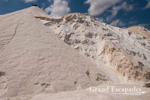 There, the salt is collected in artificially made pans. In the nearby plant it is cleaned from sand and then piled up in a huge pure white mountain, a majestic sight. It is finally scooped into bags of approx. 50 to 60 kilograms and then heaved onto trucks