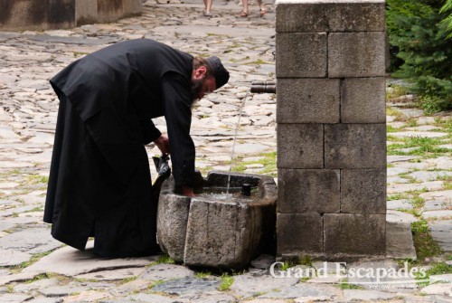 Monk collecting coins thrown in a fountain, Rila Monestary, also called "Bulgaria’s Jerusalem”, Bulgaria, Europe